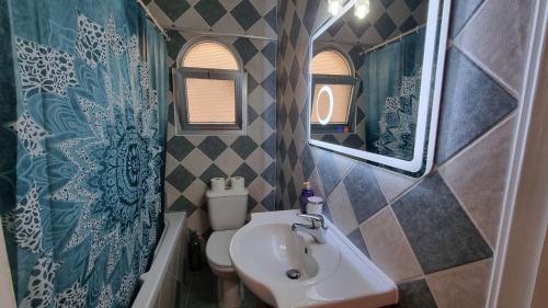 a bathroom with a sink and a toilet and a mirror at Diamond Sea View Penthouse in Paphos