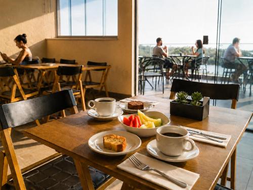 a table with cups and plates of food on it at Bella Vista Hotel in Barreirinhas