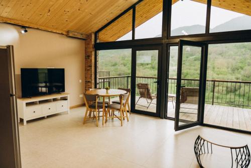 a living room with a table and chairs and windows at Casa Monti in Ijevan