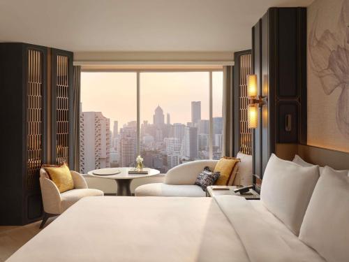 a hotel room with a bed and a view of a city at Fairmont Bangkok Sukhumvit in Bangkok