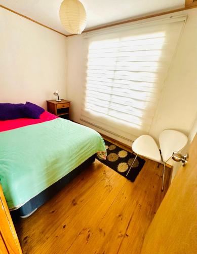 a bedroom with a bed and a window and a chair at Cabañas buchupureo in Buchupureo