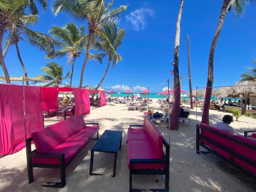 a beach with pink chairs and palm trees and the ocean at AVENTURA SUITES playa LOS CORALES - great location! in Punta Cana