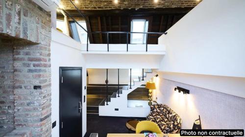 a loft with a staircase and a brick wall at Les Tanneurs in Namur