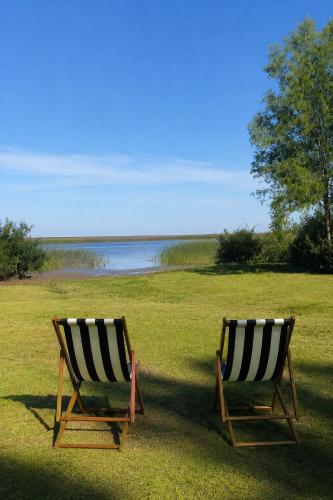two chairs sitting on the grass near a body of water at Isla Chaná Private Hideaway in Buenos Aires