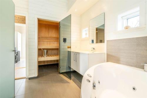 a bathroom with a tub and a sink and a mirror at 173-Ringkobing-Sondervig-Landevej-29 in Søndervig