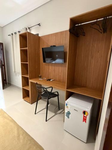 a room with a refrigerator and a desk with a television at Hotel Bom Gosto in Taiobeiras