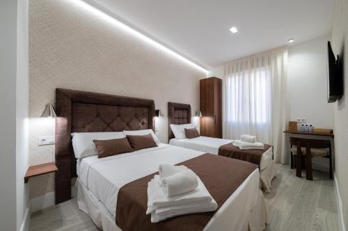 a hotel room with two beds and a television at Rosales Suites in Madrid