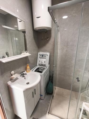 a bathroom with a sink and a washing machine at SM Studio Apartman in Tivat