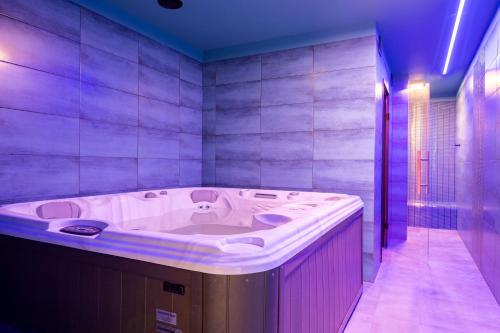 a large bath tub in a bathroom with purple lighting at Star-Dadaj Lake Camp in Barczewo