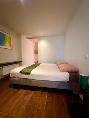 a bedroom with a bed with white sheets and pink pillows at Studio 17 in Ghent