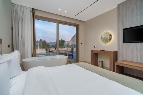 a bedroom with a bed and a tub and a television at Koun Pyramids Hotel in Cairo