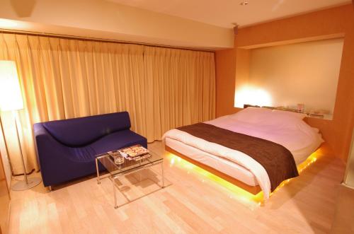 a bedroom with a bed and a blue chair at Blue Hotel Octa (Adult Only) in Sapporo