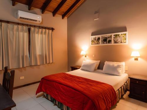 a bedroom with a bed with a red blanket at Marcopolo Suites Iguazu in Puerto Iguazú