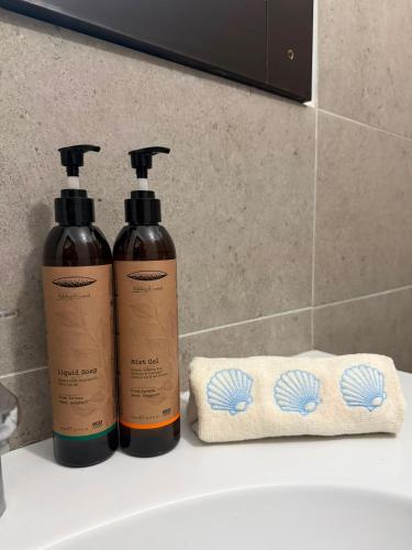 two bottles of shampoo and a towel on a sink at Hotel Amur in Corbu