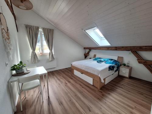 a bedroom with a bed and a desk and windows at L'appart Les Fontaines in Tramelan