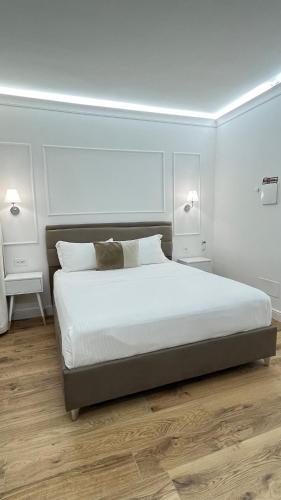 a bedroom with a large bed with white walls and wooden floors at Emy Suites in Civitavecchia