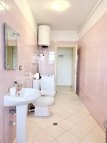 a pink bathroom with a sink and a toilet at Jacuzzi Central Apartment in Shkodër