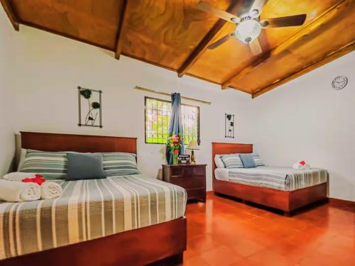 two beds in a room with a ceiling fan at Ataco Cabin Views Breakfast and Coffee in Tacuba