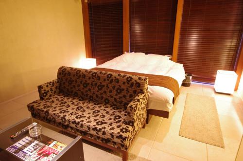 a bedroom with a bed and a couch and a chair at Blue Hotel Octa (Adult Only) in Sapporo