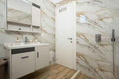 a white bathroom with a sink and a mirror at Oasis White Terra in Durrës