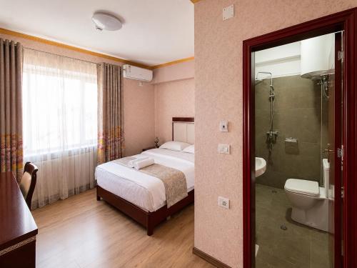 a bedroom with a bed and a shower and a toilet at British Hotel Pogradec in Pogradec