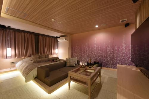 a bedroom with a bed and a couch and a table at ホテル ゼン町田 in Machida