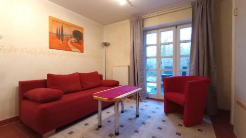 a living room with a red couch and a red chair at Strand-Appartement "Sanddornstübchen" in Dranske