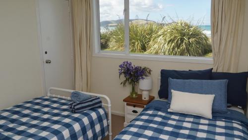 a bedroom with two beds and a window at Hideaway Beach Cottage in Curio Bay