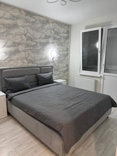 a bedroom with a large bed with a stone wall at Modern & Quiet Apartment in Chişinău