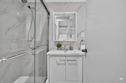 a white bathroom with a shower and a sink at Modern and spacious 3-BR basement suite in Vancouver