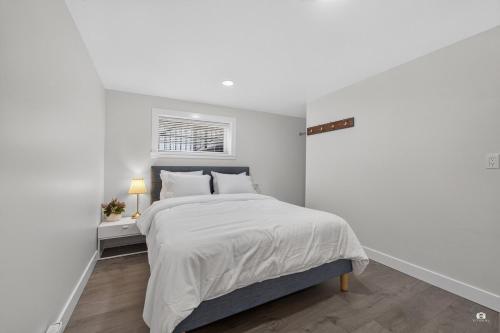 a white bedroom with a bed and a window at Modern and spacious 3-BR basement suite in Vancouver