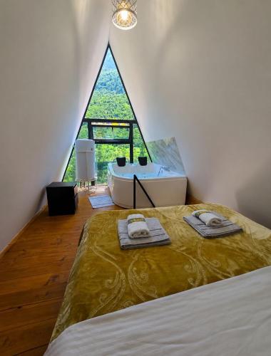 a bedroom with a bed and a bathroom with a window at Arditi's Chalets in Bogë