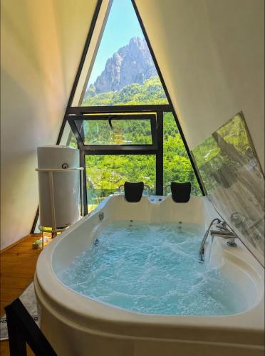 a bathroom with a tub with a large window at Arditi's Chalets in Bogë