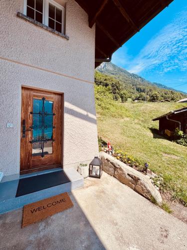 a welcome sign in front of a door of a building at Chalet Luna - Alpine Apartment by Lake Brienz in Niederried