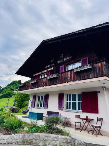 a building with a balcony and a table and chairs at Chalet Luna - Alpine Apartment by Lake Brienz in Niederried