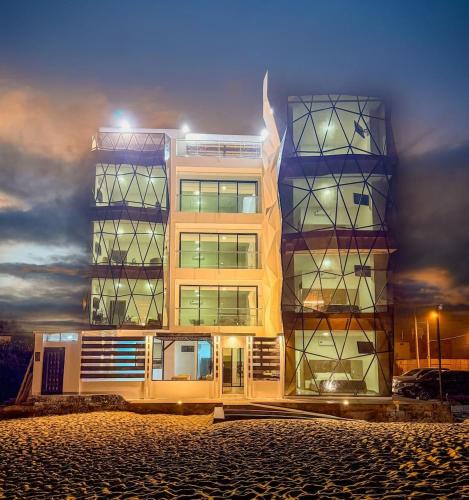 a tall building with lights on in front of it at Beachfront pool whirlpool & firepit in Montañita