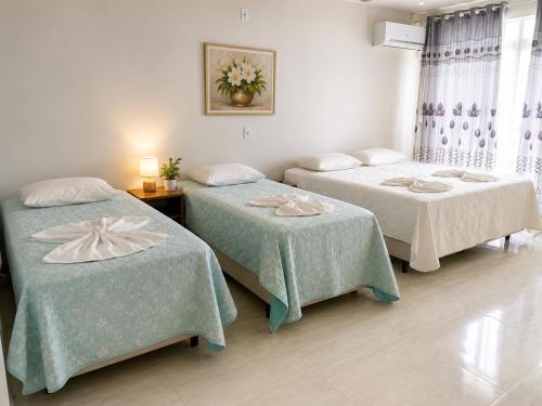 a room with two beds with green sheets at Pousada Vó Santina in Protásio Alves