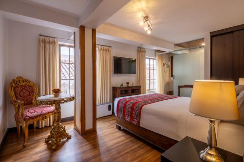 a bedroom with a bed and a table and a lamp at Hotel Monasterio del Inka Cusco in Cusco