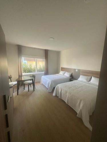 ein Hotelzimmer mit zwei Betten, einem Tisch und einem Fenster in der Unterkunft Hotel W Des Cantons in Weedon-Centre