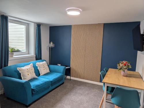 a living room with a blue couch and a table at Stylish town flat in Bude, with secure parking in Bude