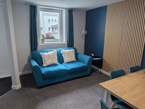 a blue couch in a room with a window at Stylish town flat in Bude, with secure parking in Bude