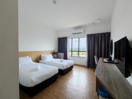 a hotel room with two beds and a flat screen tv at SF Roomstay Tunjong in Kota Bharu