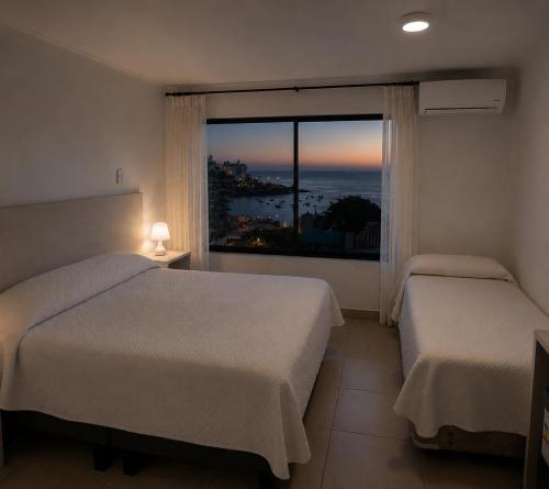 a hotel room with two beds and a large window at Hotel Carande, Papudo in Papudo