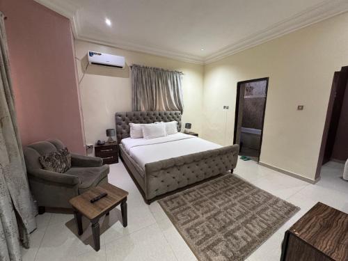 a bedroom with a bed and a couch and a chair at Zamin Suites in Kano