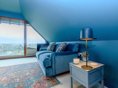 a blue living room with a blue couch and a table at River Test View in Chilbolton