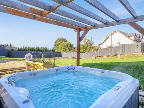 a hot tub in a backyard with a pergola at High View House in Kemeys Inferior