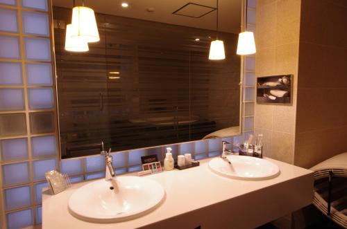 a bathroom with two sinks and a large mirror at Blue Hotel Octa (Adult Only) in Sapporo