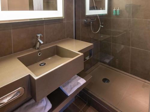 a bathroom with a sink and a shower at Novotel Saint-Quentin en Yvelines in Magny-les-Hameaux