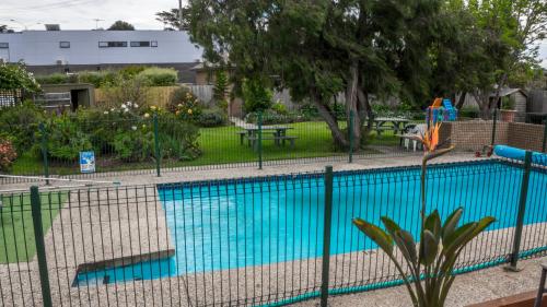 a fence around a swimming pool with a playground at Parkwood Motel & Apartments in Geelong