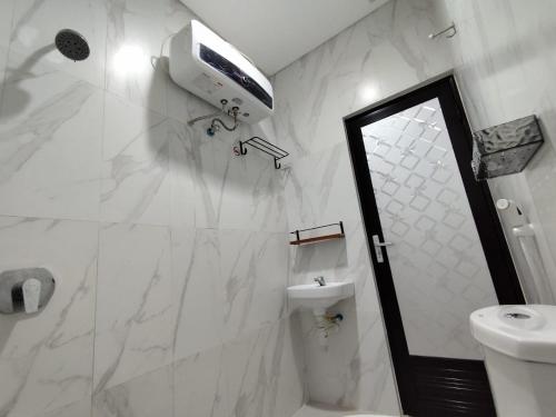 a white bathroom with a toilet and a sink at Menepi Bali in Uluwatu